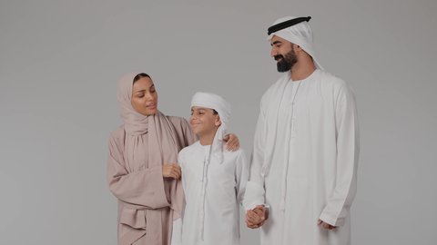 أجواء اسرية سعيدة مليئة بالحب، مشاركة الأوقات الممتعة مع الأبناء، بورتريه لام عربيه خليجيه اماراتية ترتدي العباءه الملونه تقوم بقضاء وقت ممتع برفقه زوجها تقوم باللعب مع ابنها بايماءات السعادة و السرور