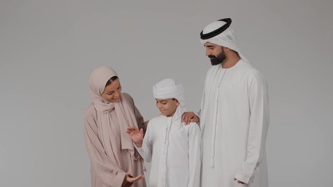 مفهوم الألفة والمحبة بين أفراد الأسرة، مشاركة الأوقات الممتعة مع الأبناء، بورتريه لام عربيه خليجيه اماراتية ترتدي العباءه الملونه تقوم بقضاء وقت ممتع برفقه زوجها تمسك بيد ابنها بايماءات السعادة و السرور