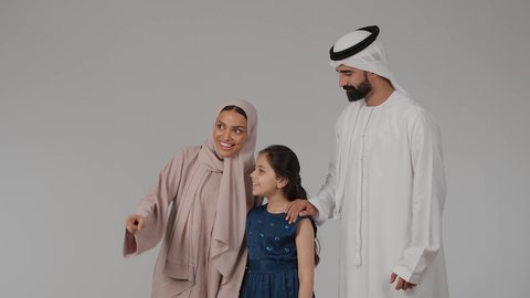 الاشارة بإصبع السبابة إلى شيء محدد، تقوية الرابط الأسري بين الأهل والأبناء، مشاركة الأوقات الممتعة مع الأبناء، المشي و التنزه مع الأطفال، بورتريه لام عربيه خليجيه اماراتية ترتدي العباءه الملونه تقوم بقضاء وقت ممتع برفقه ابنتها و زوجها