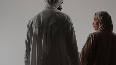 مفهوم الترابط الأسري والحفاظ على الاستقرار العائلي، مشاركه و تبادل الاحاديث بين الزوجين، بورتريه من الخلف لرجل عربي خليجي اماراتي يجرعربة الأطفال برفقة زوجته، نزهة و جولة عائلية ، قضاء أوقات عائلية ممتعة