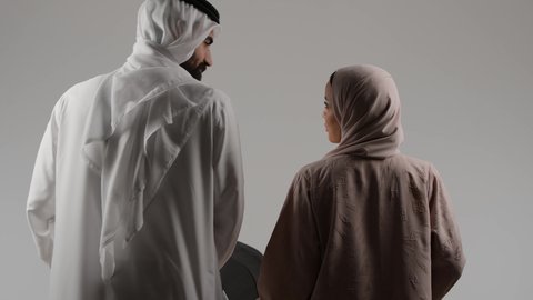 مفهوم الاسرة السعيدة المترابطة، مشاركه و تبادل الاحاديث بين الزوجين، بورتريه من الخلف لرجل عربي خليجي اماراتي يجرعربة الأطفال برفقة زوجته ، نزهة و جولة عائلية ، قضاء أوقات عائلية ممتعة