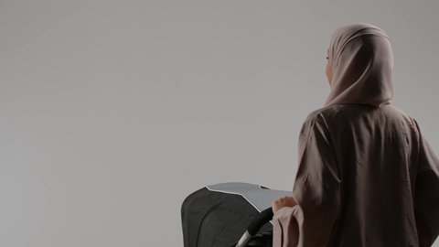 التجول والترفيه، تحمل المسؤولية والعناية بالأطفال، إيماءات الحب والحنان على الصغار، بورترية من الخلف لأم عربيه خليجيه اماراتية ترتدي العباءه الملونه تقوم بجرعربه الاطفال