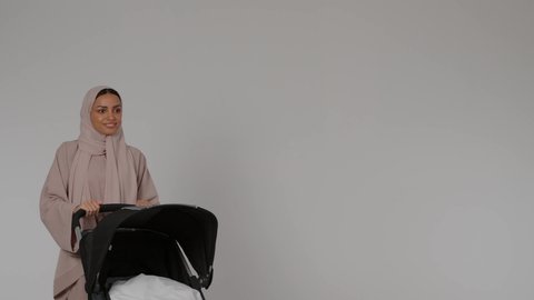 تحمل المسؤولية والعناية بالأطفال، إيماءات الحب والحنان على الصغار، بورترية لأم عربيه خليجيه اماراتية ترتدي العباءه الملونه تقوم بجر عربه الاطفال بسعادة و سرور