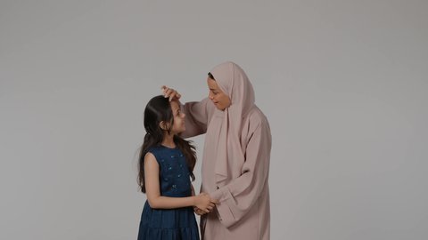 أجواء أسرية ممتعة، قضاء وقت ممتع مع الابناء، مفهوم المحبة والألفة والترابط الأسري، بورتريه لامراة عربيه خليجيه اماراتية ترتدي العباءه الملونه برفقه ابنتها تنظر الى الكاميرا بايماءات السعادة و السرور