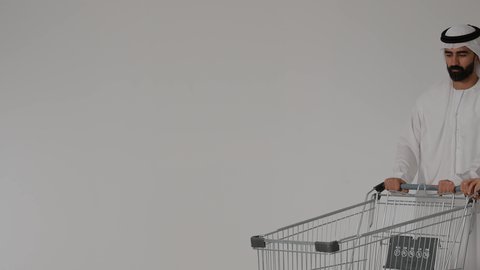 حب الآباء لأبنائهم, الترابط الأسري والاستمتاع مع العائلة, قضاء الأوقات برفقة الأبناء، بورترية لرجل عربي خليجي اماراتي يرتدي الزي التقليدي يقوم بجر عربة التسوق برفقه ابنه ، الاستفاده من العروض والتخفيضات الموسميه