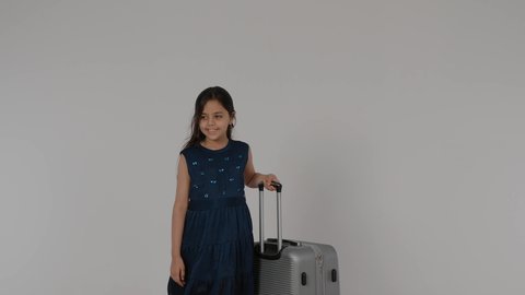 قضاء وقت ممتع في السياحه بالعطلة الصيفيه,  بورترية لطفله عربيه خليجيه اماراتية ترتدي الفستان الملون تمسك بيديها حقيبه السفر بايماءات السعادة و السرور، مفهوم الاستعداد والتجهيز للسفر
