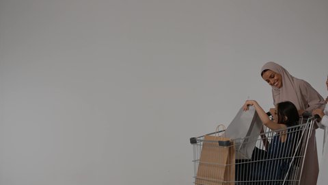 أجواء عائلية سعيدة، الاستفاده من العروض والتخفيضات الموسميه ، بورتريه لعائلة عربية خليجية اماراتية ترتدي الزي التقليدي تقوم بالتبضع و شراء المستلزمات، بنت خليجيه اماراتية تجلس داخل عربة التسوق، التجول والترفيه ، ايماءات السعادة و السرور