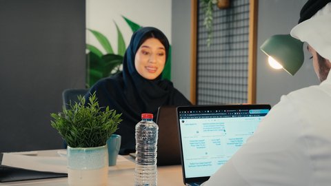 إدارة شؤون الأعمال وتنظيمها، استخدام التقنيات الحديثة والمتطورة، تصوير مقرب لامراة عربية خليجية اماراتية محجبة مبتسمة تقوم بعمل اجتماع عن بعد عبر الحاسوب المحمول، اداء المهام للتطور المهني وتحقيق الاهداف