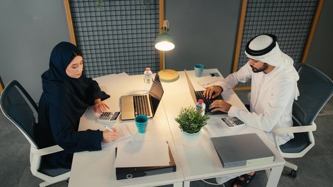 مفهوم المشاركة و التعاون في العمل، مهن ووظائف ادارية مكتبية، مفهوم الإدارة المتعاونة، تعلم اساليب العمل والتطوير المهني، العمل الجماعي وروح الفريق الواحد، وضع الخطط الاستراتيجية لتحقيق الأهداف، زملاء عمل عربيون خليجيون اماراتيون يجلسون داخل مقر الشركة