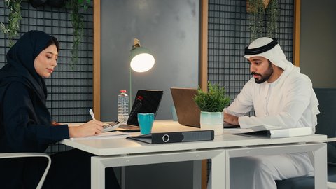 العمل الجماعي وروح الفريق الواحد، وضع الخطط الاستراتيجية لتحقيق الأهداف، مفهوم الإدارة المتعاونة، زملاء عمل عربيون خليجيون اماراتيون يجلسون داخل مقر الشركة ، تعلم اساليب العمل والتطوير المهني، مهن ووظائف ادارية مكتبية، المساواة بين الرجل الامرأة