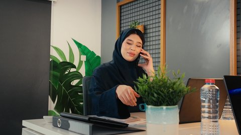 الاستمتاع بتناول المشروب، التوظيف في المكاتب والشركات الاماراتية، استخدام التقنيات الحديثة والتكنولوجيا بالمجال الإداري، الإجابة والرد على مكالمات العمل الهاتفية عبر الجوال، تصوير مقرب لامراة عربيه خليجيه اماراتيه ترتدي العباءة السوداء تجلس على المكتب وأمامها الحاسوب المحمول