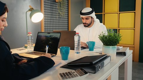 اجراء مكالمه هاتفيه عبر الهاتف المحمول، الاستمتاع بتناول المشروبات، دمج الأجهزة التقنية الحديثة بالأعمال المكتبية، دراسة أوراق البيانات الإحصائية, تطوير المشاريع و الاستثمارات, إدارة و تقسيم المهام، تصوير لفريق عمل عربي خليجي اماراتي  يقوم بالعمل على الحاسب المحمول