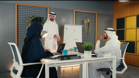 تعلم اساليب العمل والتطوير المهني، التفاهم والتعاون بين الزملاء، مجموعة من الموظفين العرب الخليجيين الاماراتيين يعقدون اجتماع داخل مقر الشركة، وضع الخطط الاستراتيجية لتحقيق الأهداف، العمل الجماعي وروح الفريق ضمان فهم واضح وشامل للاعمال باستخدام السبورة