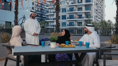 التسلية و الاستمتاع فى وقت الفراغ، مفهوم تبادل الأحاديث والدردشات، ايماءات الاندماج و الضحك و السرور، نقاشات وحوارات، اصدقاء عرب خليجيين اماراتيين يرتدون الزي التقليدي يستمتعون بقضاء وقت ممتع في احد المقاهي الاماراتية
