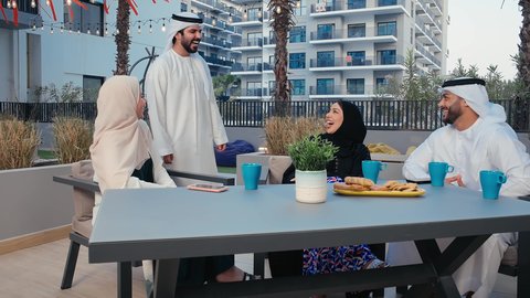 The concept of exchanging conversations and chats, gestures of integration, laughter and pleasure, discussions and dialogues, Arab Gulf Emirati friends wearing traditional dress enjoying a pleasant time in one of the Emirati cafes