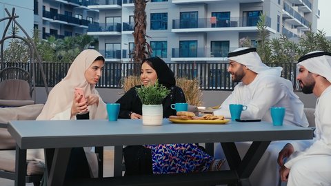 تصفح مواقع الانترنت عبر الهاتف المحمول بايماءات السعادة و السرور ، نقاشات وحوارات، اصدقاء عرب خليجيين اماراتيين يستمتعون بقضاء وقت ممتع في احد المقاهي الاماراتية، امراه عربيه خليجيه اماراتيه تمسك بيدها الجوال
