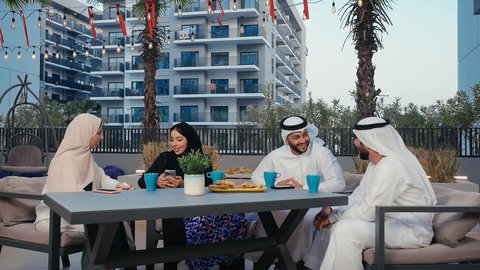 نقاشات وحوارات، وناسة وتعارف، نزهه في الهواء الطلق، أصدقاء عرب خليجيين اماراتيين يرتدون الزي التقليدي يستمتعون بقضاء وقت ممتع في احد المقاهي الاماراتية