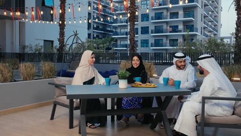 Taking memorable selfies with your mobile phone, having a great time on the weekend, enjoying hot drinks, chatting with friends, friendly get-togethers, Emirati Gulf Arab friends having a great time in an Emirati cafe.