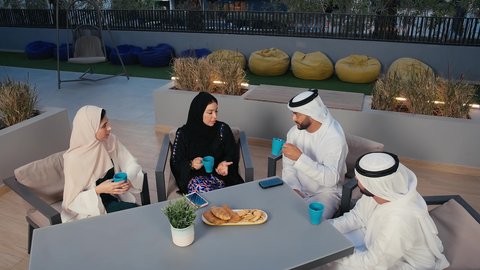 Building successful social relationships between friends, sitting outdoors, friendly get-to-know-you sessions, Emirati Gulf Arab friends enjoying exchanging conversation in an Emirati cafe, chatting with friends, enjoying drinks