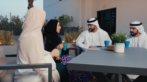 Expressions of happiness and pleasure at a gathering of friends, enjoying hot drinks outside, restaurants and cafes in the Emirates, friendly get-to-know-you sessions, Emirati Gulf Arab friends enjoying exchanging talk in an Emirati cafe, chatting and chatting with friends