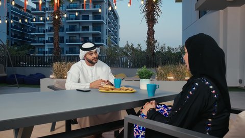 بناء علاقات وتعارف, صداقات ومعارف، قضاء عطلة نهاية الأسبوع في المطاعم والكافيهات، رجل عربي خليجي اماراتي يرتدي الكندورة و الغتره يقوم بالاستمتاع بقضاء وقت ممتع فى احدي المقاهي برفقه زوجته