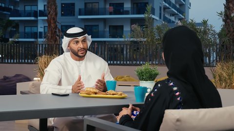 وناسة وتعارف، قضاء عطلة نهاية الأسبوع  في المطاعم والكافيهات، رجل عربي خليجي اماراتي يرتدي الكندورة و الغتره يقوم بالاستمتاع بقضاء وقت ممتع فى الهواء الطلق برفقه زوجته ، أنشطة عائلية ترفيهية