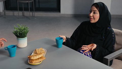 Spending a pleasant time outdoors in a pleasant atmosphere, going out on a family evening, an Arab Gulf Emirati couple sitting in a cafe in the United Arab Emirates, strengthening marital relations and bonds of love and affection, drinking cold drinks and delicious seasonal juices