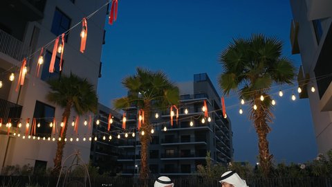 The concept of entertainment, spending a good time with friends, having a refreshing drink, two Emirati Gulf Arab men wearing kandura and ghutra exchanging conversations and discussions inside a cafe with gestures of pleasure and happiness