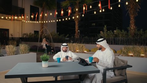 تبادل الأفكار وبناء علاقات اجتماعية, الاستمتاع في التحدث والنقاش في إحدى المقاهي الفاخرة في الامارات, زملاء عمل عرب خليجيون اماراتيون في اجتماع عمل خارج الشركة يقومان بمشاهده التابلت, قضاء وقت ممتع مع الأصدقاء في عطلة نهاية الأسبوع ، الاستمتاع بتناول المشروبات
