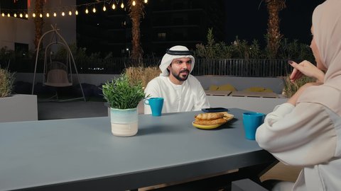 عطلة نهاية الاسبوع، ايماءات تدل على السعادة والاستمتاع بالتحدث، مفهوم الرابطة الزوجية والألفة بين الزوجين، تصوير مقرب لزوجان عربيان خليجيان امارتيان يرتديان الزي التقليدي يجلسان فى احد المقاهي ، تناول المشروبات الباردة، نقاشات وحوارات، قضاء أوقات ممتعة