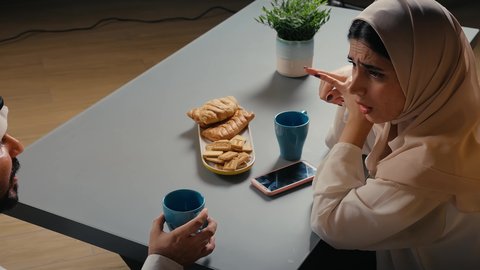 الاستمتاع بتناول المشروبات، قضاء أوقات ممتعة، تصوير مقرب لزوجان عربيان خليجيان اماراتيان يرتديان الزي التقليدي يستمتعان بتبادل الحديث في احد المقاهي الاماراتية، نقاشات وحوارات، أجواء عائلية سعيدة