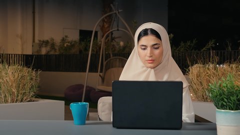 استخدام التكنولوجيا الحديثة والمتطورة، إنجاز مهام العمل عن بعد من خلال الانترنت، تصوير مقرب لشابة عربية خليجية اماراتية تعمل على الحاسب المحمول بايماءات الاندماج و التركيز، سيده سعودية تجلس فى احد مقاهي الامارات العربية