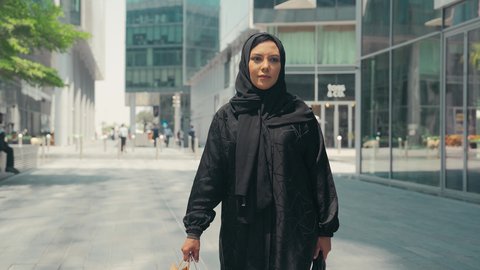 A Saudi woman enjoying the pleasure of shopping, modern Gulf women's abayas, interest in fashion, beauty and elegance, buying women's clothes and accessories, taking advantage of seasonal discounts, a photo of a young Arab Gulf Emirati woman wearing an abaya and hijab, carrying shopping bags