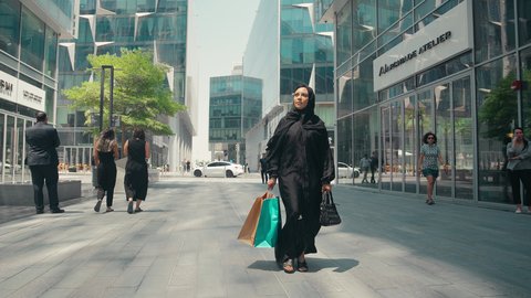 عباءات خليجيه نسائيه عصريه، الإهتمام بالموضة والجمال والأناقة، شراء الملابس والاكسسوارات النسائيه ، الاستفادة من التخفيضات الموسمية، سيدة سعودية تستمتع بمتعة الشراء ،  تصوير لشابة عربية خليجية اماراتية ترتدي العباءة والحجاب ، تحمل اكياس التسوق