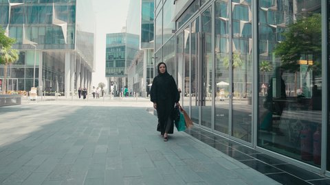 الإهتمام بالموضة والجمال والأناقة، شراء الملابس والاكسسوارات النسائيه ، الاستفادة من التخفيضات الموسمية، سيدة سعودية تستمتع بمتعة الشراء ، عباءات خليجيه نسائيه عصريه، تصوير لشابة عربية خليجية اماراتية ترتدي العباءة والحجاب ، تحمل اكياس التسوق