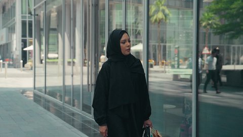 الاستفادة من التخفيضات الموسمية، سيدة سعودية تستمتع بمتعة الشراء ، عباءات خليجيه نسائيه عصريه، الإهتمام بالموضة والجمال والأناقة، شراء الملابس والاكسسوارات النسائيه ، تصوير لشابة عربية خليجية اماراتية ترتدي العباءة والحجاب ، تحمل اكياس التسوق