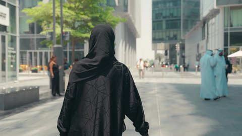 عباءات خليجيه نسائيه عصريه، الإهتمام بالموضة والجمال والأناقة، شراء الملابس و الاكسسوارات النسائيه ، تصوير من الخلف لشابة عربية خليجية اماراتية ترتدي العباءة والحجاب ، تحمل اكياس التسوق ، الاستفادة من التخفيضات الموسمية، سيدة سعودية تستمتع بمتعة الشراء