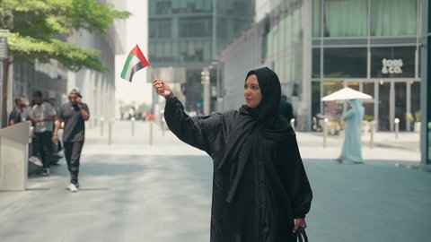 العيد الوطني الإماراتي ، يوم استقلال الإمارات ، مفهوم حب الوطن ، تصوير لمرأة عربية خليجية إماراتية ترتدي العباءة والحجاب ، تحمل علم الإمارات العربية المتحدة، الإحتفال باليوم الوطني الإماراتي