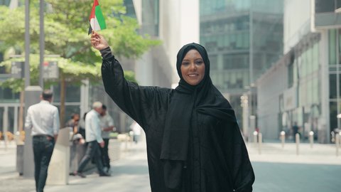 تصوير لمرأة عربية خليجية إماراتية ترتدي العباءة والحجاب ، تحمل علم الإمارات العربية المتحدة، العيد الوطني الإماراتي ، الإحتفال باليوم الوطني الإماراتي، يوم استقلال الإمارات ، مفهوم حب الوطن