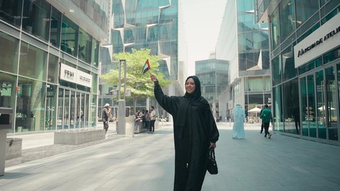 الاستمتاع بجمال الطبيعة ، سيدة سعودية تستعد لبدء العطلة خارج البلاد , السياحة في إجازة الصيف, قضاء رحلة صيفية ممتعة, تصوير لشابة عربية خليجية اماراتية محجبة ترتدي العباءة تمسك بيدها حقيبة السفر بإيماءات السرور