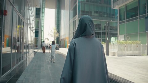 عباءات خليجيه نسائيه عصريه، الإهتمام بالموضة والجمال والأناقة،  تصوير من الخلف لشابة عربية خليجية اماراتية ترتدي العباءة والحجاب ، تحمل اكياس التسوق ، الاستفادة من التخفيضات الموسمية، شراء الملابس و الاكسسوارات النسائيه ، سيدة سعودية تستمتع بمتعة الشراء