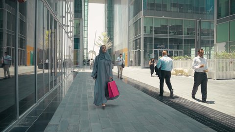 Taking advantage of seasonal discounts, interest in fashion, beauty and elegance, a photo of a young Arab Gulf Emirati woman wearing an abaya and hijab, carrying shopping bags, buying women's clothes and accessories, modern Gulf women's abayas, a Saudi woman enjoying the pleasure of shopping