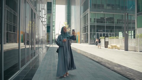 استخدام الهاتف المحمول والتقنيات الحديثه، اجراء مكالمة فيديو ،توثيق اللحظات السعيدة، امرأة عربية خليجية سعودية ترتدي العباءة والحجاب، سيدة اماراتية تنظر بتعابير السرور تقوم باستخدام الهاتف المحمول ، نزهة وجولة فى الهواء الطلق