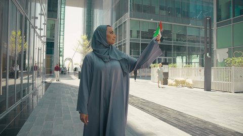 يوم استقلال الإمارات ، العيد الوطني الإماراتي ، الإحتفال باليوم الوطني الإماراتي، مفهوم حب الوطن ، تصوير لمرأة عربية خليجية إماراتية ترتدي العباءة والحجاب ، تحمل علم الإمارات العربية المتحدة