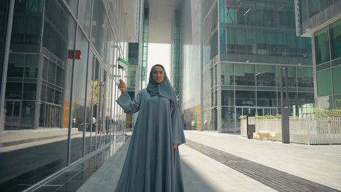 العيد الوطني الإماراتي ، يوم استقلال الإمارات ، الإحتفال باليوم الوطني الإماراتي، مفهوم حب الوطن ، تصوير لمرأة عربية خليجية إماراتية ترتدي العباءة والحجاب ، تحمل علم الإمارات العربية المتحدة