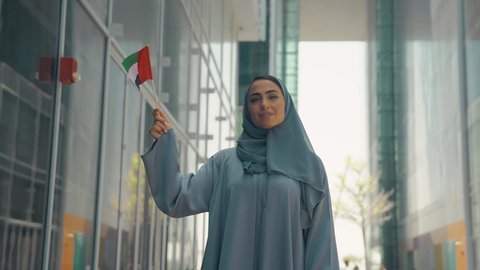 الإحتفال باليوم الوطني الإماراتي، العيد الوطني الإماراتي ، يوم استقلال الإمارات ، مفهوم حب الوطن ، تصوير لمرأة عربية خليجية إماراتية ترتدي العباءة والحجاب ، تحمل علم الإمارات العربية المتحدة