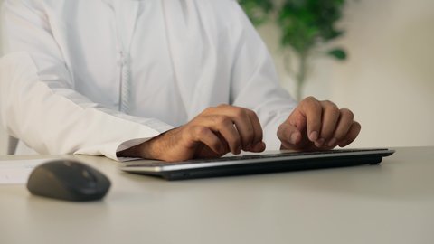 إدارة شؤون الأعمال وتنظيمها، إتمام مهام العمل في المكتب، دمج العمل مع التقنية والتكنولوجيا، تطور الشركات الاماراتية، استخدام جهاز تقني حديث ومتطور، تصوير مقرب لرجل عربي خليجي اماراتي يستخدم الحاسوب، مهنة ووظيفة مكتبية