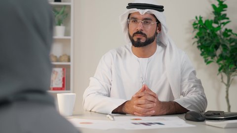 عقد اجتماع داخل مقر الشركة، التفاهم والتعاون بين الزملاء ووضع الخطط الاستراتيجية، موظفان عربيان خليجيان اماراتيان يتعلمان اساليب العمل والتطوير المهني، تبادل الخبرات والمعلومات لتحقيق الاهداف، روح الفريق الواحد والعمل الجماعي، تصوير من الخلف لموظفة محجبة