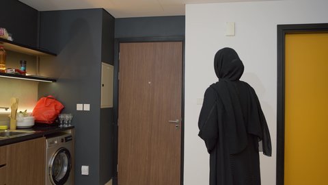 مفهوم المحبة والألفة بين الزوجين، الاستعداد للذهاب إلى دوام العمل بنشاط, رجل عربي خليجي اماراتي يرتدي الكندورة والغترة يأتي إلى منزله, الاهتمام بالأناقة والمظهر الخارجي، سيده اماراتية تقوم باستقبال زوجها اثناء عودته من  العمل بإيماءات السرور والسعادة