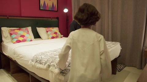 Passion for reading books and novels, doing fun activities at home, teaching children to be educated and read, a Saudi woman spending quality time with her children, an Arab Gulf Emirati mother wearing a black abaya sitting on the bed next to her son and reading stories and tales before bed